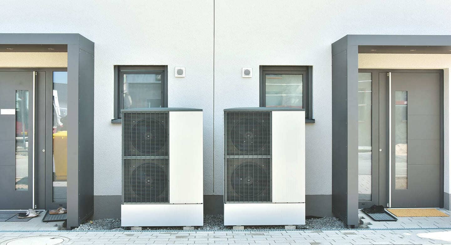 Zwei Wärmepumpen mit wenig Abstand vor einem Reihenhaus