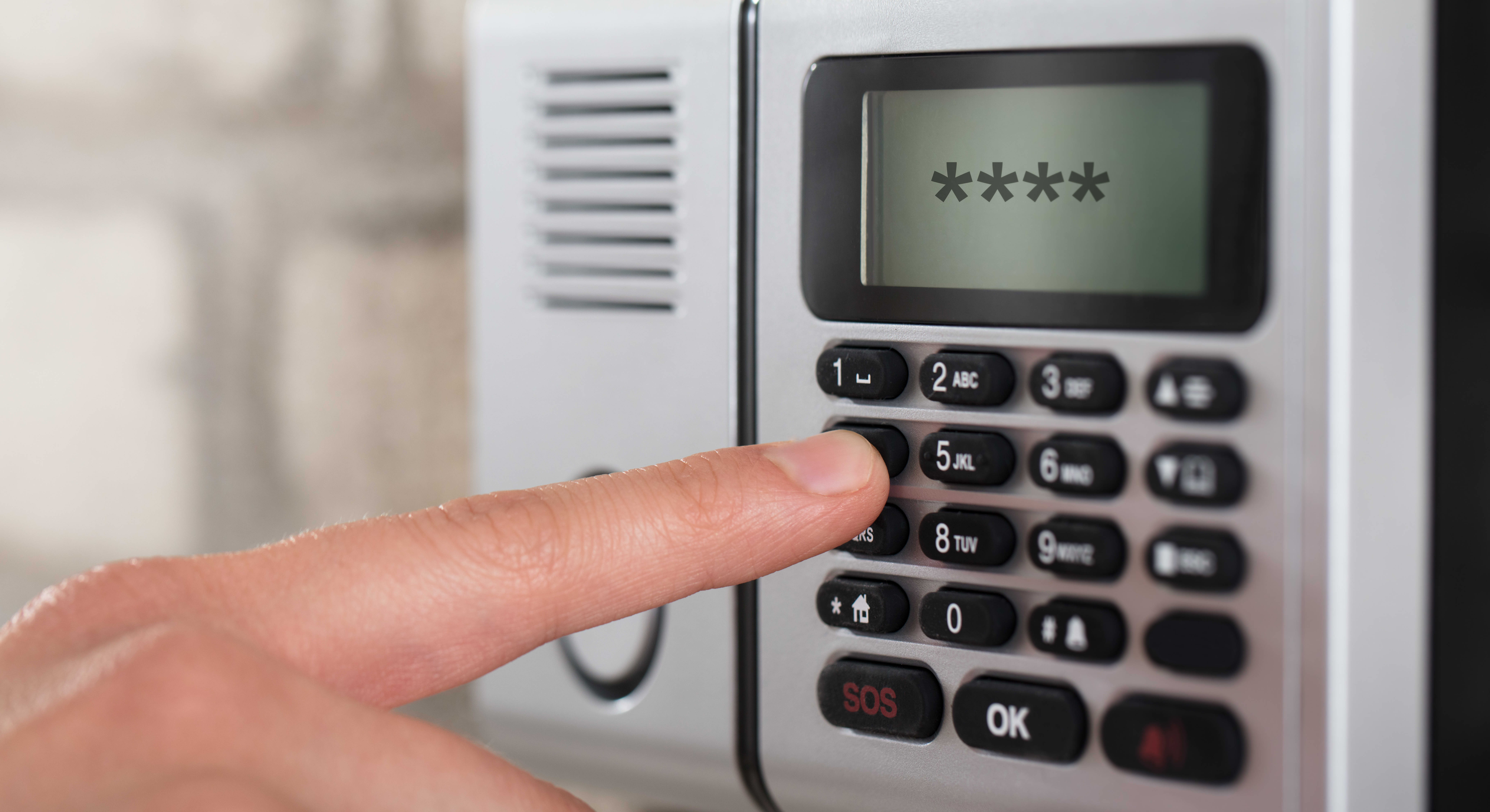 Nahaufnahme der Hand einer Person, die den Sicherheitscode an einer Alarmanlage eingibt