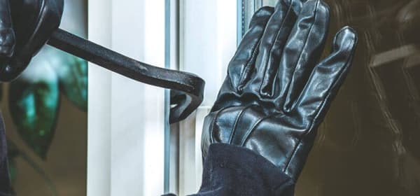 Einbruch mit Brecheisen an Fenster – Nahaufnahme mit Handschuhen
