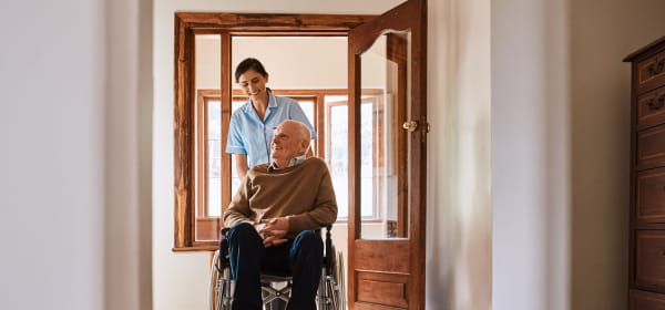 Junge Frau schiebt älteren Mann im Rollstuhl