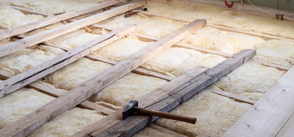 Holzdielen auf Glaswolle, auf denen ein Hammer liegt