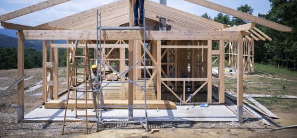 Bauarbeiter arbeiten auf Baustelle eines modernen Holzhauses