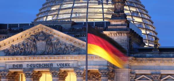 Reichstag in Berlin in der Dämmerung mit deutscher Flagge