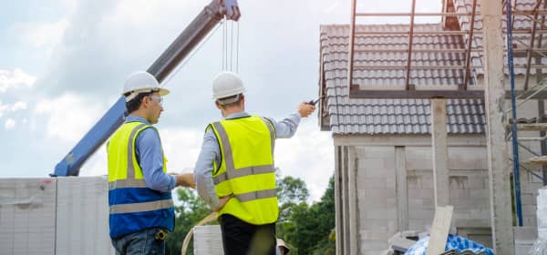 Bauleute vor dem unfertigen Neubau eines Wohngebäudes