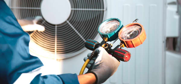 Mechaniker überprüft Kältemittel in einer Wärmepumpe mit einem Manometer