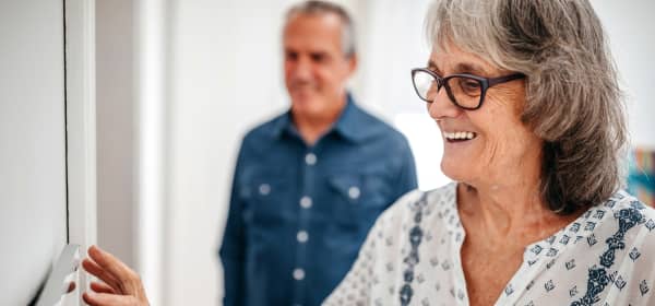 Lächelnde Seniorin stellt ihren digitalen Heizungsregler ein