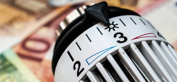 Nahaufnahme eines Heizthermostats mit Euroscheinen im Hintergrund