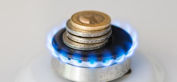 Euromünzen liegen auf einem kleinen Gasbrenner mit blauer Flamme