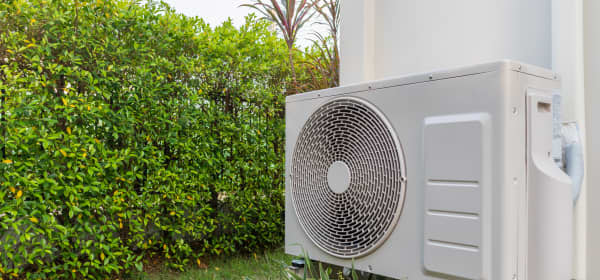 Wärmepumpe am Haus neben Hecke zum Nachbargrundstück