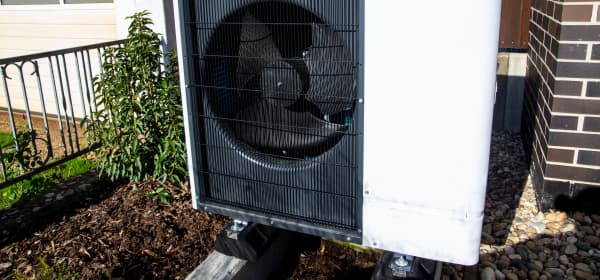 Weiße Luft-Wasser-Wärmepumpe vor Einfamilienhaus