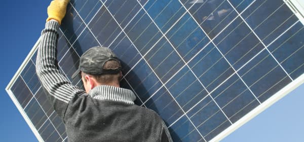 Handwerker trägt ein Solarmodul zur Installation einer Photovoltaikanlage