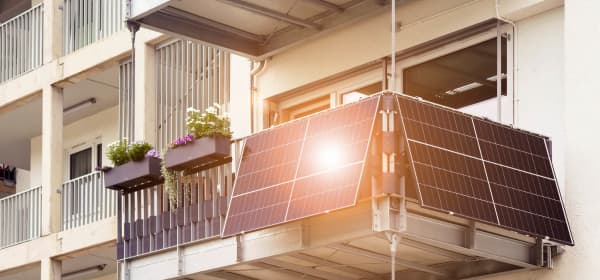 Balkon mit Balkonkraftwerk, dessen Module das Sonnenlicht reflektieren
