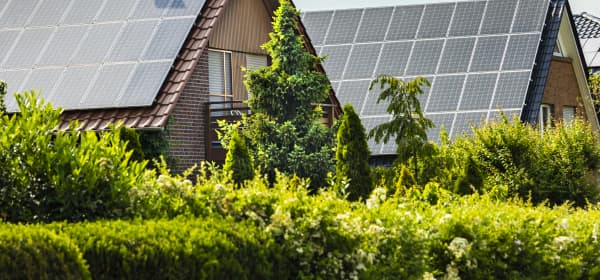 Zwei Wohnhäuser mit Solaranlagen auf den Dächern im Grünen