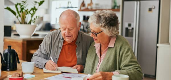 Älteres Paar sitzt am Küchentisch über Rechnungen