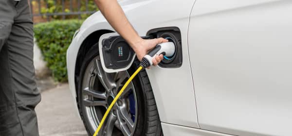 Mann lädt sein Elektroauto vor seinem Haus