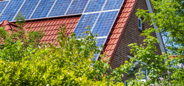 Sonnenkollektoren auf einem roten Giebeldach bei Sonnenschein