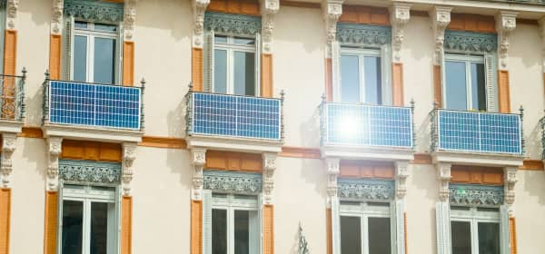 Fassade eines sanierten Altbaus mit Solarmodulen an mehreren Balkonen