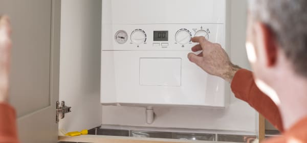 Aufnahme eines Mannes, der eine Kombitherme einer Gasheizung abliest