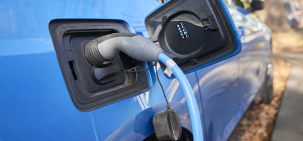 Nahaufnahme eines blauen E-Autos, das gerade geladen wird