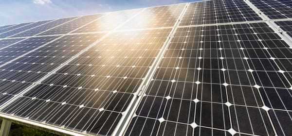 Nahaufnahme von schwarzen Photovoltaik-Modulen auf einem Dach, auf die die Sonne scheint