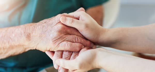 Eine jüngere und eine ältere Person halten sich die Hände, Nahaufnahme der Hände