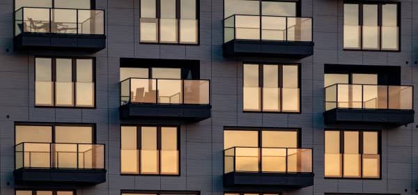 Abendsonne spiegelt sich in Fenstern und Balkonverglasungen an einem modernen Mehrfamilienhaus