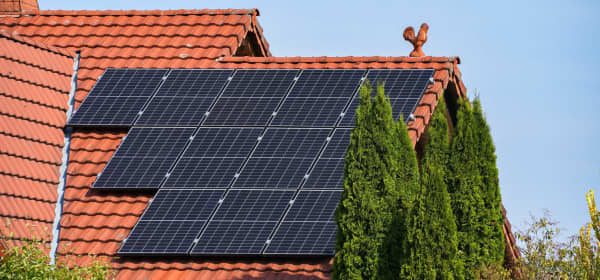 Solarmodule auf rotem Ziegeldach eines Wohnhauses