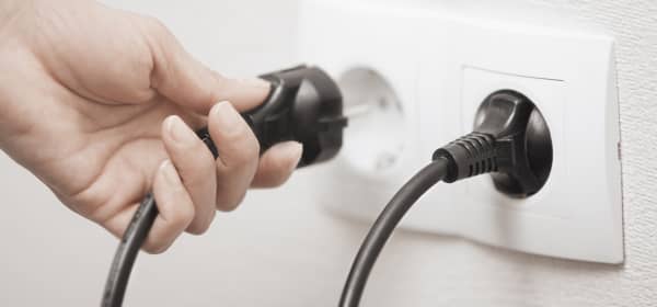 Frau steckt einen Stecker in eine Steckdose, Nahaufnahme ihrer Hand