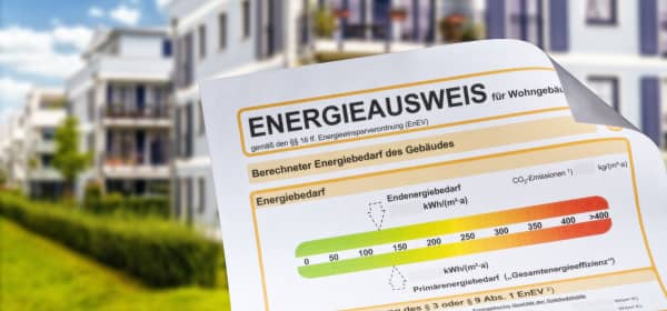 Energieausweis mit modernem Mehrfamilienhaus im Hintergrund