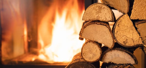 Aufgestapelte Holzscheite vor einem brennenden Kamin