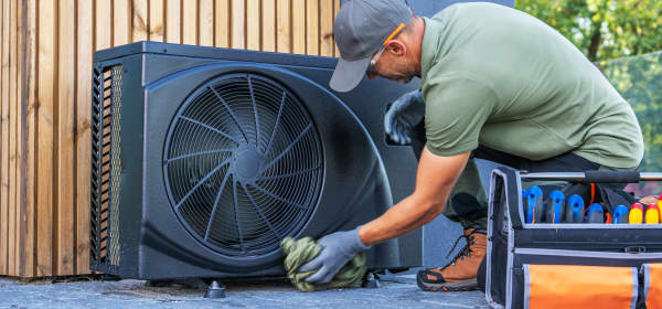 Monteur arbeitet im Freien an einer schwarzen Wärmepumpe