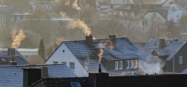 Wohnhäuser mit qualmenden Schornsteinen im Winter