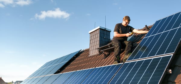 Handwerker installiert Solarmodule auf dem Dach eines Einfamilienhauses