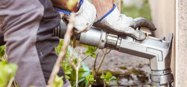 Mann in Arbeitskleidung nutzt einen Anschluss zum Betanken mit Heizöl an einem Haus