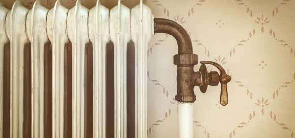 Alter Gliederheizkörper in Raum mit altmodischer beiger Tapete