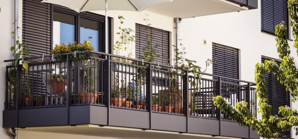 Balkon mit Pflanzen und Sonnenschirm an einem modernen Mehrfamilienhaus