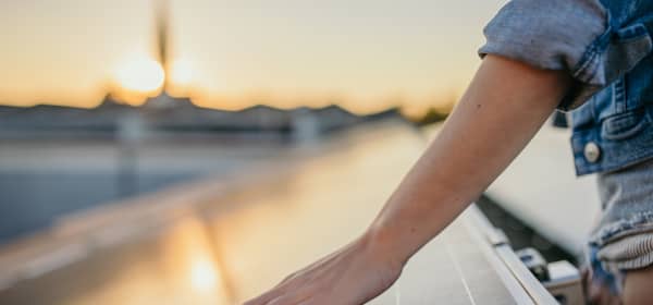 Hand berührt Solarpanel vor Sonnenuntergang