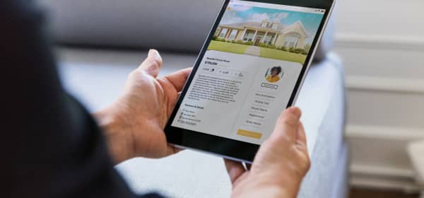 Person sieht sich das Inserat einer Immobilie auf einem Tablet an