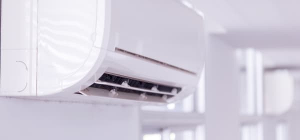 Nahansicht des Innengeräts einer fest installierten Klimaanlage in einem Raum mit weißen Wänden