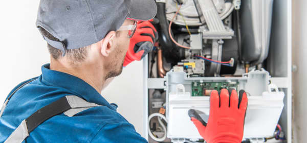 Handwerker in Arbeitskleidung arbeitet an einer Gastherme