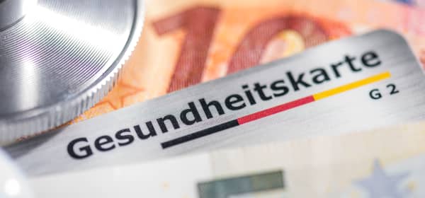 Nahaufnahme von Stethoskop, Gesundheitskarte und mehreren Euroscheinen