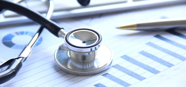 Stethoskop, Kugelschreiber, Finanzübersicht und Computertastatur auf einem Tisch