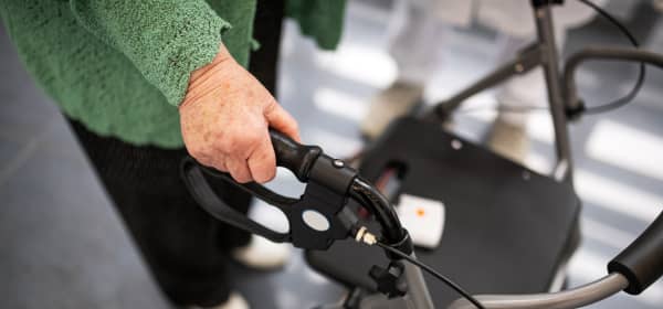 Seniorin in schwarzer Hose und grünem Oberteil mit einem Rollator