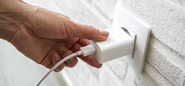 Nahaufnahme der Hand einer Person, die einen Stecker in eine Steckdose steckt