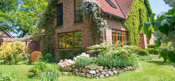 Einfamilienhaus mit Klinkerfassade und roter Dacheindeckung in einem Garten