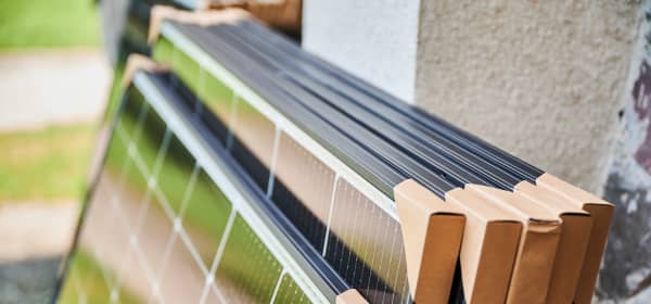 Mehrere verpackte Solarmodule lehnen am Äußeren eines Gebäudes