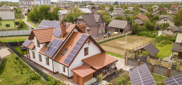 Wohnhäuser im Grünen mit Dach-Solaranlagen und freistehenden Solarmodulen
