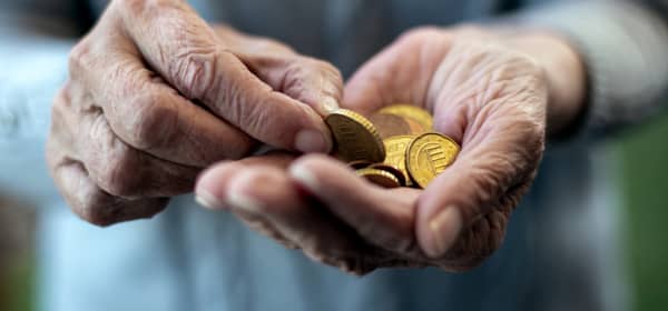Nahaufnahme der Hände einer älteren Person. Sie hält Euromünzen in der Hand.