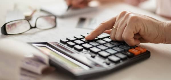 Nahaufnahme der Hände einer älteren Frau, die auf einem Taschenrechner tippt