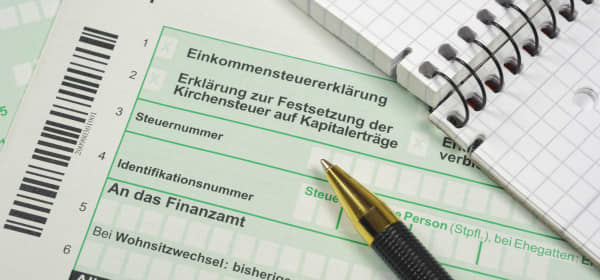 Formulare zur Einkommensteuererklärung mit Notizblock und Kugelschreiber